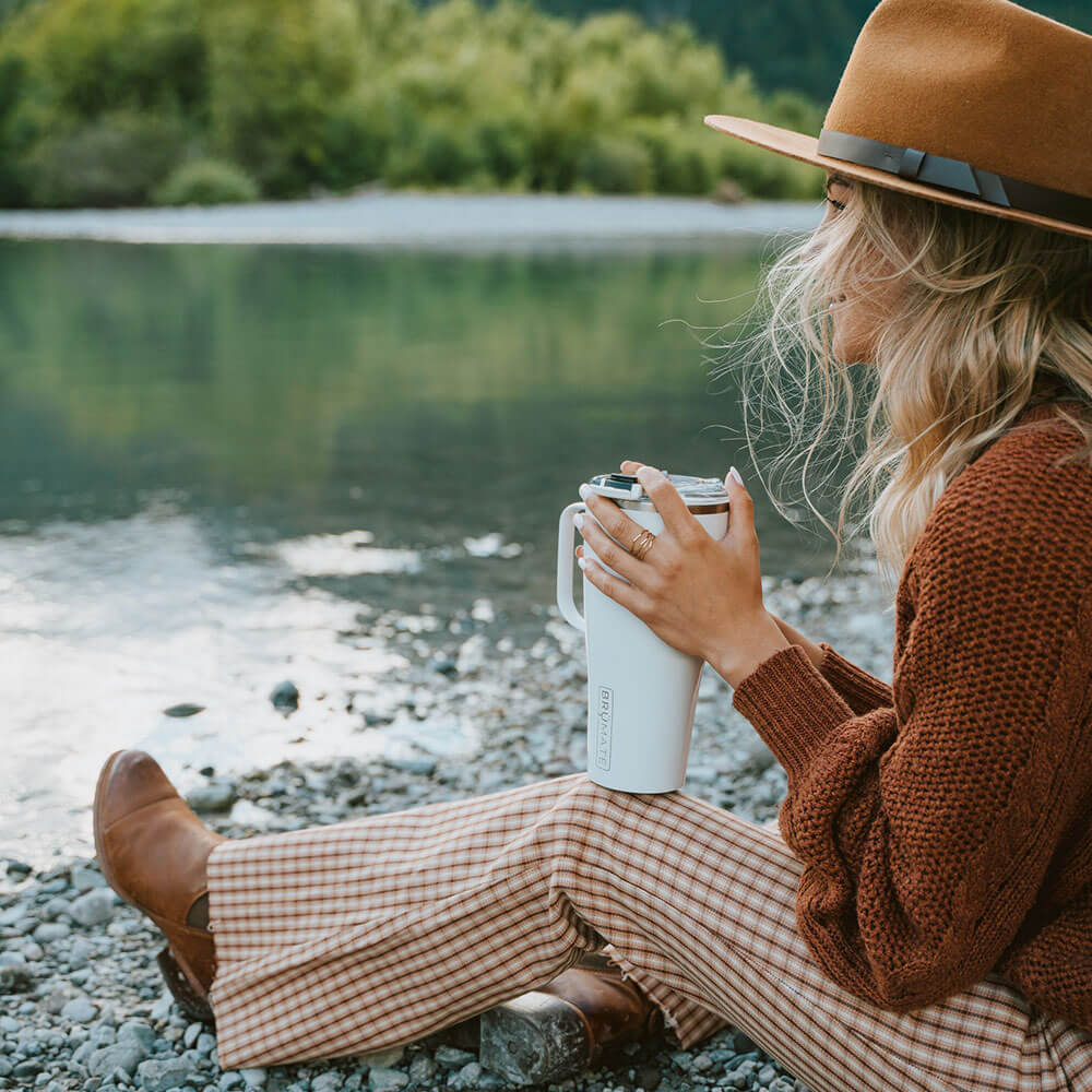 woman sitting by a lake holding a brumate